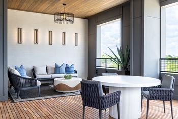 A modern living room with a white sofa, a round table, and a wooden ceiling.